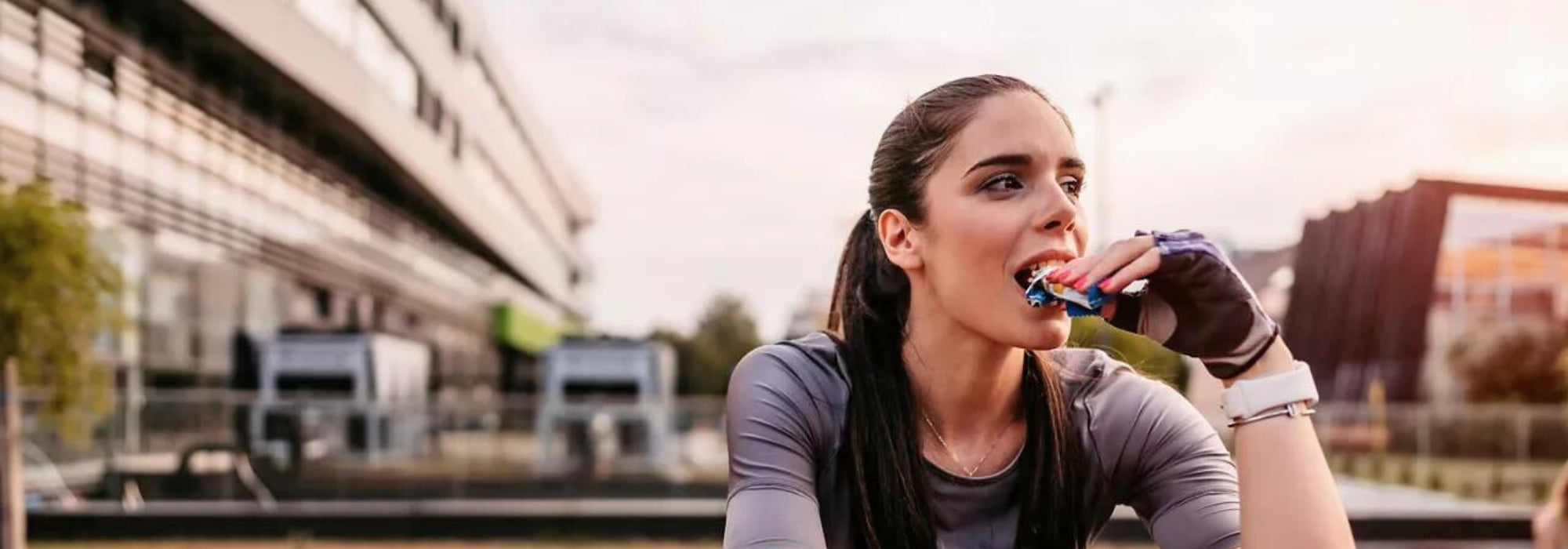 young women workout outside eating energy bar fitness